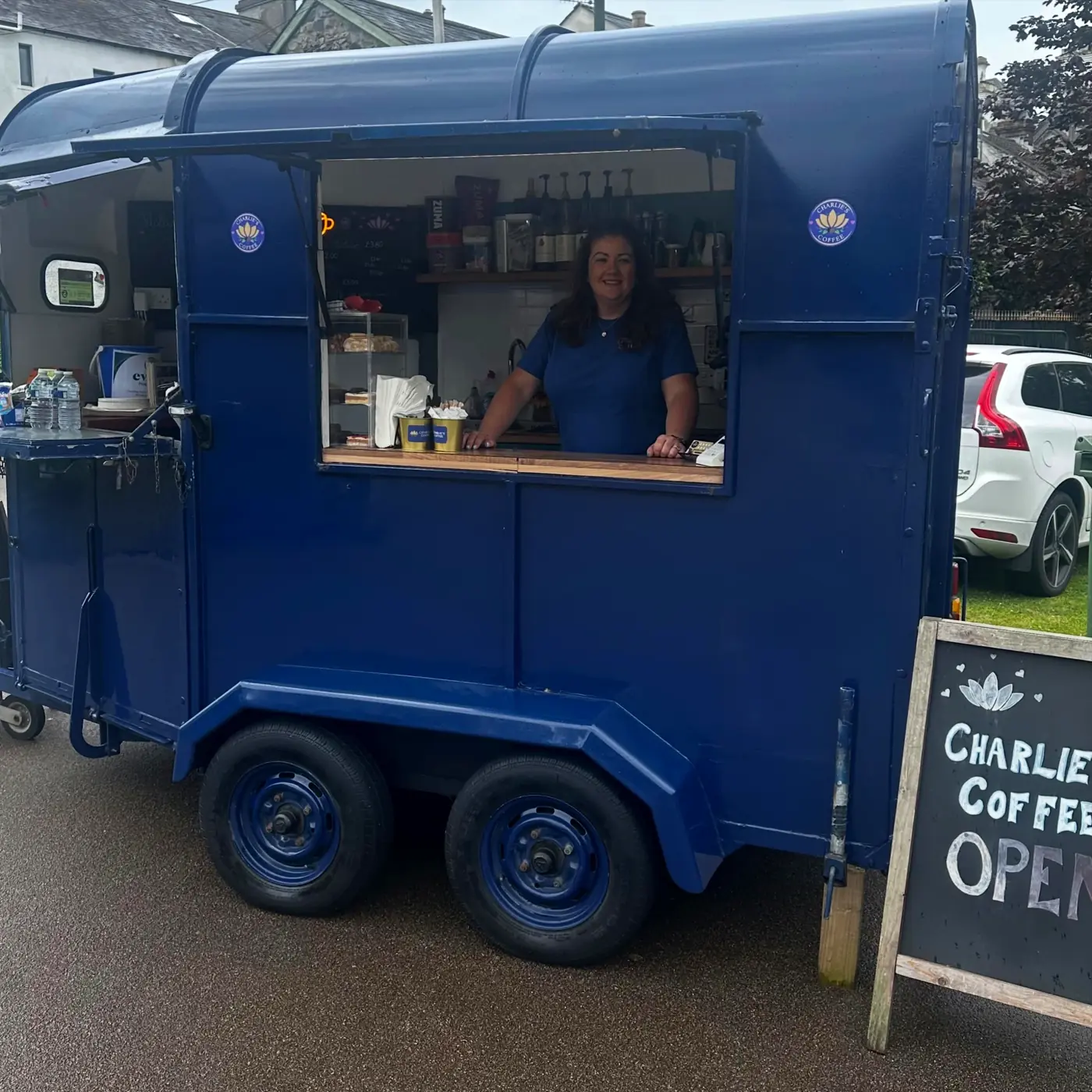 Charlie's blue coffee trailer and barista at an outdoor event